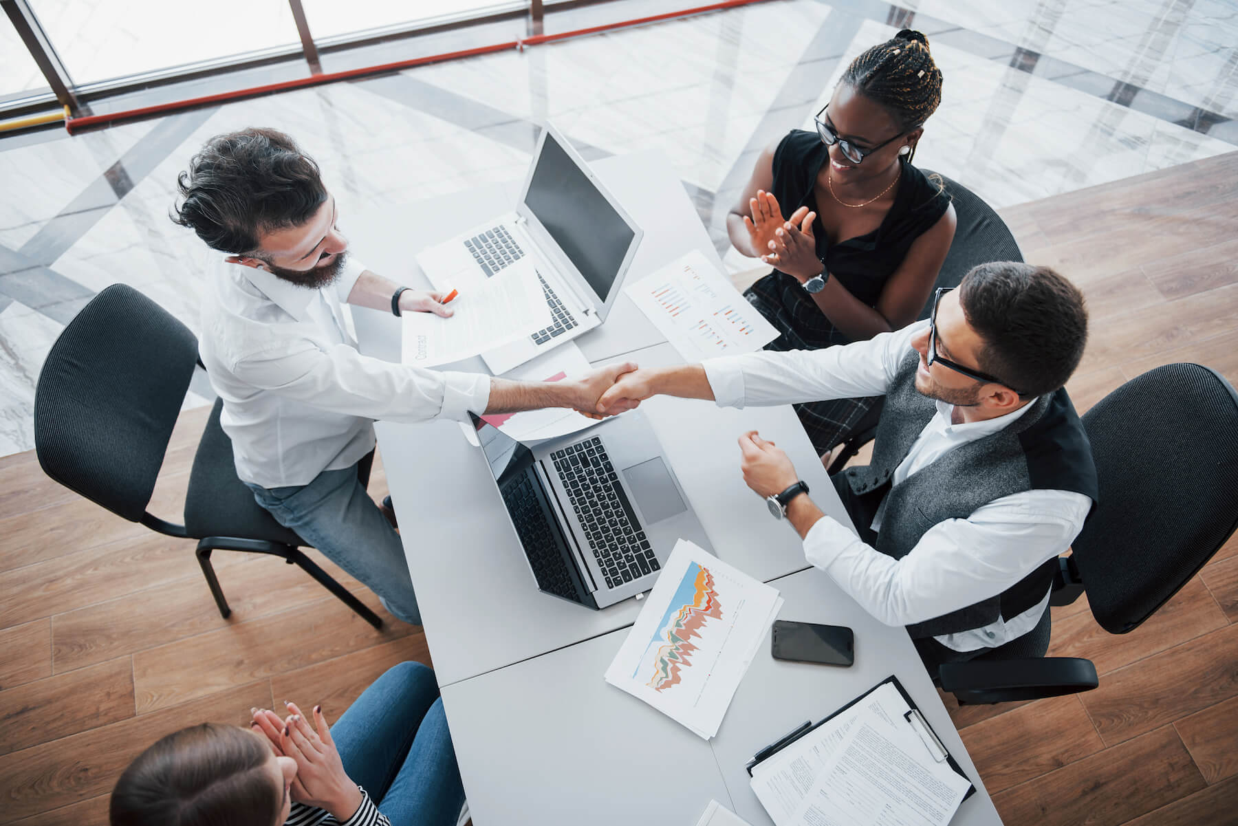 Group of office workers shaking hands over a table